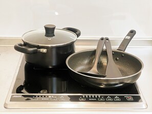 A black electric stove with a pot and a frying pan on it. - RUKA (Osaka)