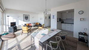 A modern living space with a dining area, kitchen, and seating area. - Seaview Apartment on the Beach - Free Parking (Ostend)