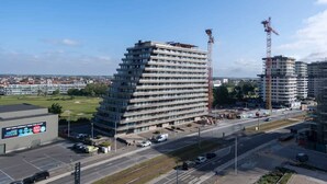 A multi-story hotel with a modern design, featuring a prominent entrance and a parking area. - Seaview Apartment on the Beach - Free Parking (Ostend)