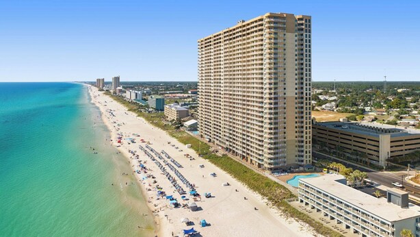 Un hotel moderno con vistas a la playa, varios balcones y un garaje.