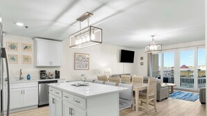 A modern kitchen with white cabinetry, a central island, and a dining area with a sofa and chairs.