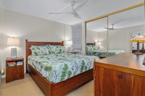 Une chambre à coucher avec un lit en bois, des lampes de chevet, une table de chevet avec des livres, un miroir et des ventilateurs de plafond.