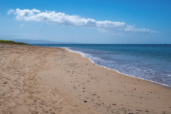 A sandy beach with gentle waves and a clear sky.