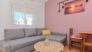 A living room with a grey sofa, a round wooden coffee table, a small wooden table, a chair, and a painting on the wall. - Apartment Jozanovic (Vir)