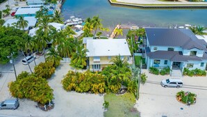 An aerial view of a coastal property with a large house, a swimming pool, and several parked cars. - Sundance: Ocean View, Dock, Pool, Elevator, Beach, Kayaks, Ice Machine (Marathon)