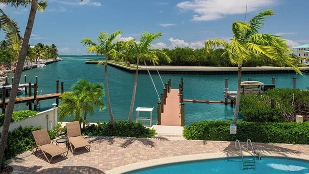 A pool area with lounge chairs, a dock, and a view of the ocean. - Sundance: Ocean View, Dock, Pool, Elevator, Beach, Kayaks, Ice Machine (Marathon)