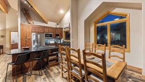 A kitchen with wooden cabinets, a stainless steel refrigerator, and a large window.