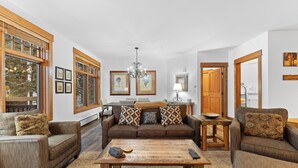 A cozy living room with a brown sofa set, a wooden coffee table, and framed artwork on the walls.