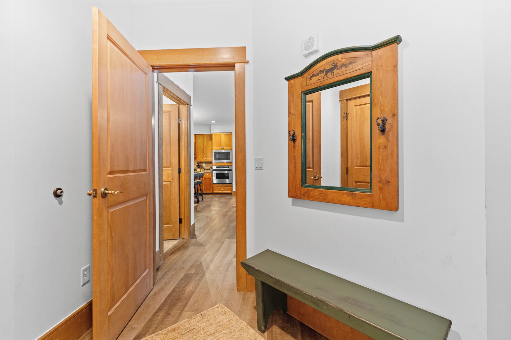 A hallway with wooden doors, a bench, and a mirror on the wall.