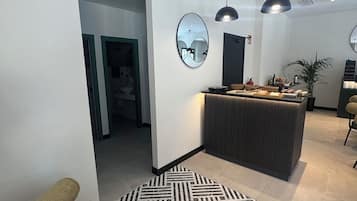 Um interior moderno com uma mesa de recepção, um tapete estampado e luminárias pendentes.