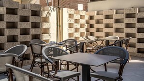 Une terrasse extérieure avec des chaises et des tables en osier, entourée de murs en pierre.