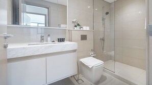 Ein modernes Badezimmer mit einer Duschkabine, einem Marmorwaschbecken und einer Toilette.