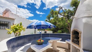 A pool area with a blue umbrella, a stone bench, and a brick oven. - Garden House- Pool, Self Check-in, Private Entrance (Carvoeiro)
