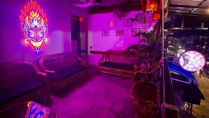 Una habitación tenuemente iluminada con muebles tradicionales y un letrero de neón en la pared.