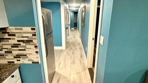 A narrow hallway with light wood flooring, blue walls, and white trim.