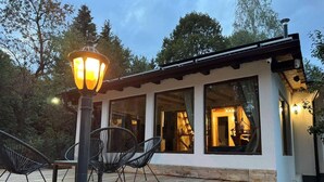 A wooden deck with outdoor seating, a lamp post, and a building with large windows. - Villa Yarema Mountain Relax With Hot Jacuzzi & Sauna (Samokov)