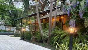 A pathway leading to a building with a covered patio area, surrounded by lush greenery and potted plants. - Ziziphus Tree Villas (Thissamaharama)