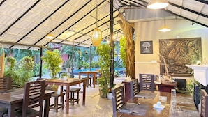 An indoor restaurant with wooden tables and chairs, hanging lights, and potted plants. - Ziziphus Tree Villas (Thissamaharama)