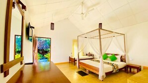 A room with a four-poster bed, a wooden table, and a view of a tropical landscape through the window. - Ziziphus Tree Villas (Thissamaharama)