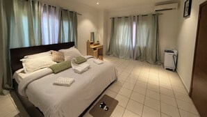 Een hotelkamer met een groot bed, een bureau met stoel, een airconditioning en een deur.