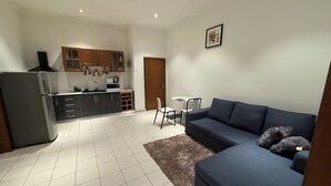A compact living space with a kitchenette, a sofa, and a dining area. - Mayama airport apartment (Accra)
