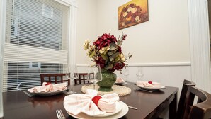 Une table à manger dressée avec des assiettes, des serviettes et un vase de fleurs.