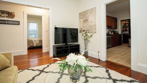 Un salon avec une télévision, un canapé et un vase décoratif rempli de fleurs.
