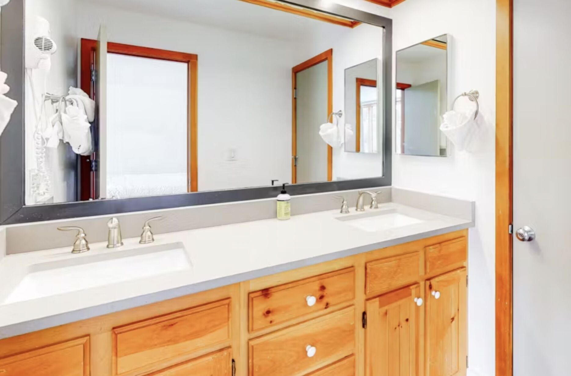 A bathroom with two sinks, wooden cabinets, and a large mirror.