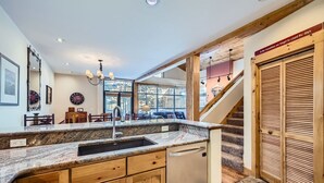 A kitchen with granite countertops, wooden cabinets, a built-in dishwasher, and a large window offering a view of the outdoors. - 8712 Ski Tip Townhomes 3 Bedroom Townhouse (Keystone)
