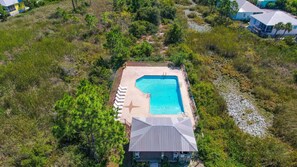 An aerial view of a property with a swimming pool, surrounded by dense vegetation and a few buildings. - The Rookery Iii 4007 3 Bedroom Cottage (Gulf Shores)