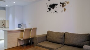 En moderne stue med sofa, sofabord og et arbejdsområde med computer og stol.