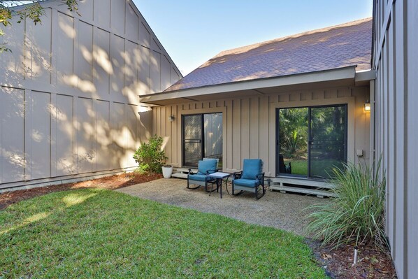 A patio with two chairs and a table, a large window, and a door.