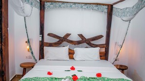 Un lit avec une tête de lit en bois, une literie blanche et des fleurs rouges décoratives.