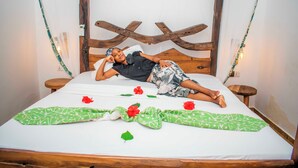 Un lit avec une tête de lit en bois, une literie blanche et des couvertures à motifs verts et blancs.
