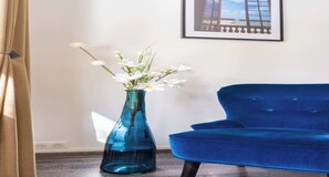 A blue sofa and a blue vase with white flowers. - Bright & Contemporary 2BD Apartment (Paris)
