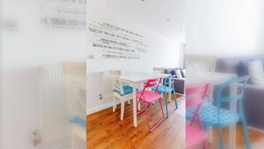 A room with a white table and chairs, a radiator, and a bed with pillows.