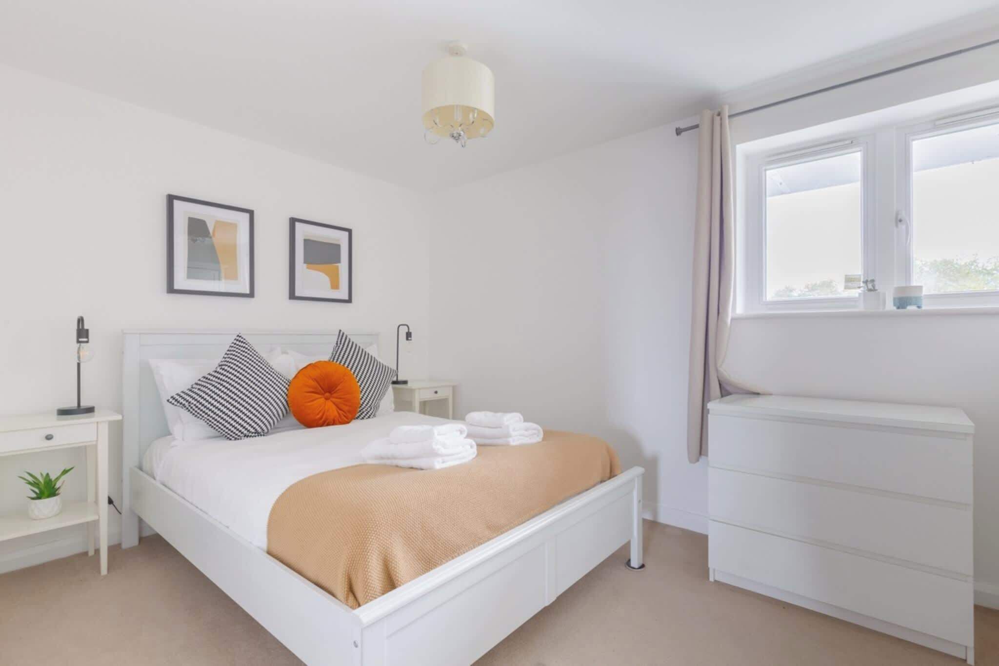 A modern bedroom with a bed, bedside tables, a radiator, and a window.