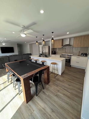 Una cucina moderna con isola centrale, elettrodomestici integrati e illuminazione a sospensione.