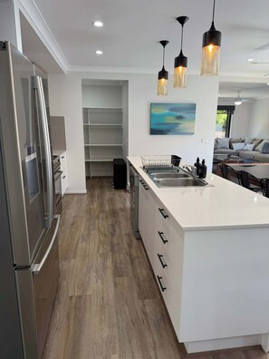 A modern kitchen with a central island, stainless steel appliances, and pendant lighting. - 4BR Mount Clear Manor - Sleep Up To 8 Guests! (Mount Clear)