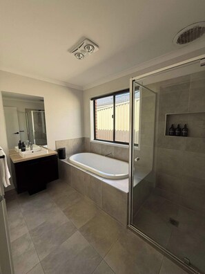 A modern bathroom with a glass-enclosed shower, a freestanding bathtub, and a vanity with a mirror. - 4BR Mount Clear Manor - Sleep Up To 8 Guests! (Mount Clear)