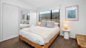 Un dormitorio con cama, mesita de noche, lámpara y un cuadro en la pared.