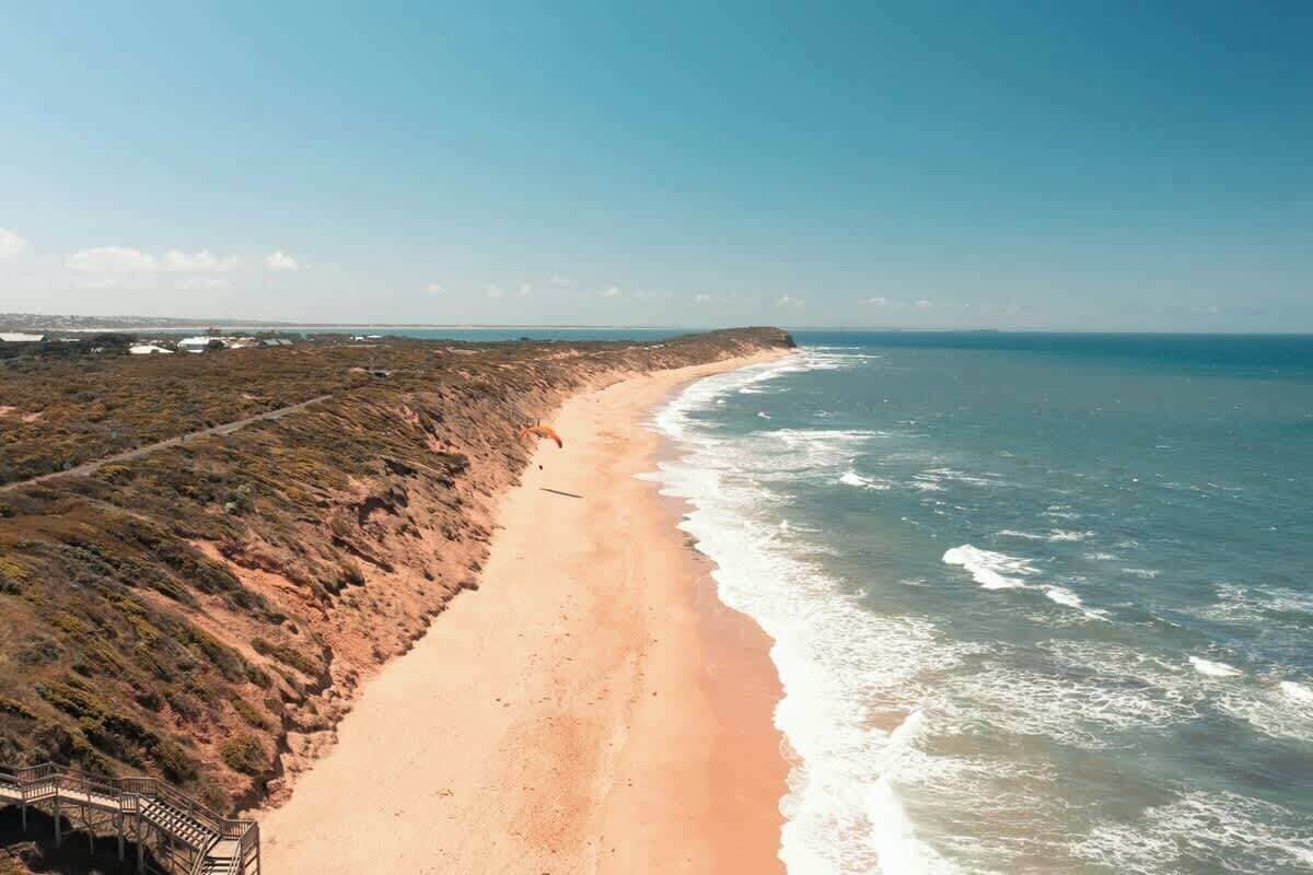 En strand vid kusten med en träpromenad och fri utsikt över havet.