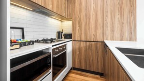 Una cocina moderna con armarios de madera, encimeras blancas, una estufa y un horno.