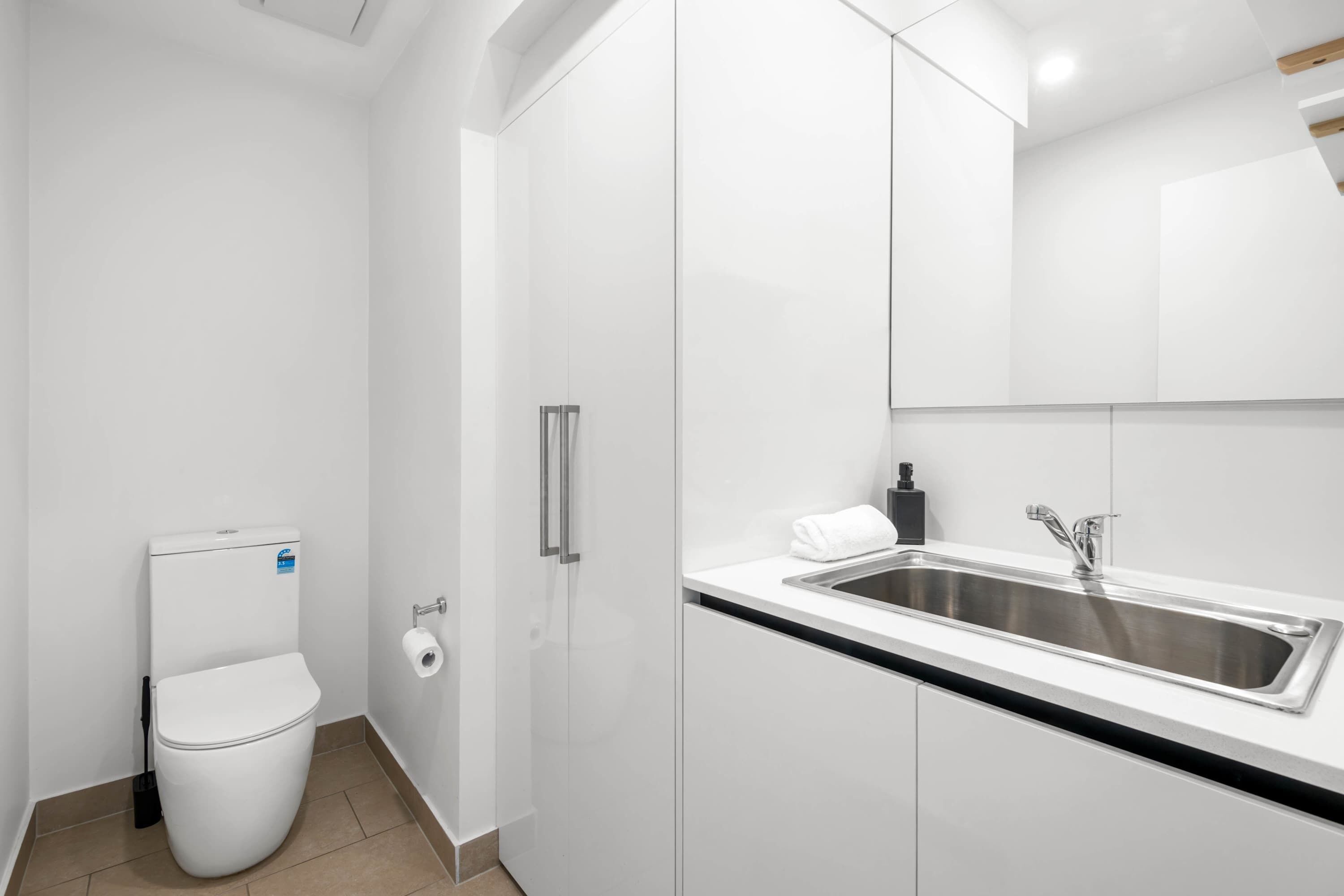 A modern bathroom with a toilet, sink, and cabinets.