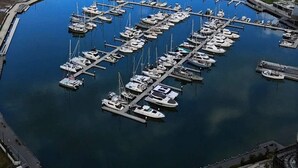 Une vue aérienne d’une marina où de nombreux bateaux sont amarrés, entourée d’eau et de terre.