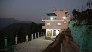 Un edificio de varios pisos con balcón, escaleras y vistas del paisaje circundante.