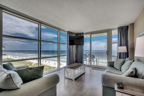 Ein modernes Hotelzimmer mit großem Balkon, einer Couch, einem Couchtisch und einem Fernseher.