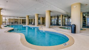 An indoor swimming pool with multiple lanes, large pillars, and a lifeguard on duty sign. - 🌴🐠Lazy River + Indoor/Outdoor Pools | Oceanfront | South Wind 205 (Myrtle Beach)