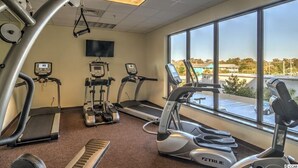 A gym with treadmills, elliptical machines, and a stationary bike, with a large window offering a view of the outside. - 🌴🐠Lazy River + Indoor/Outdoor Pools | Oceanfront | South Wind 205 (Myrtle Beach)