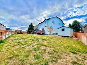 A residential backyard with a house, a wooden fence, and a small shed. - GolfSim HotTub PS5 Sauna Thtr Pooltbl 6BR 5BA 420 (Thornton, CO, 80602)